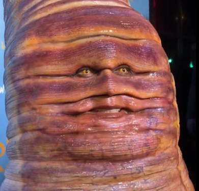 Heidi Klum Wormsuit meme template - Heidi Klum in a full-body worm prosthetic costume at her 2022 Halloween party. The worm is segmented, pink, and far too reali