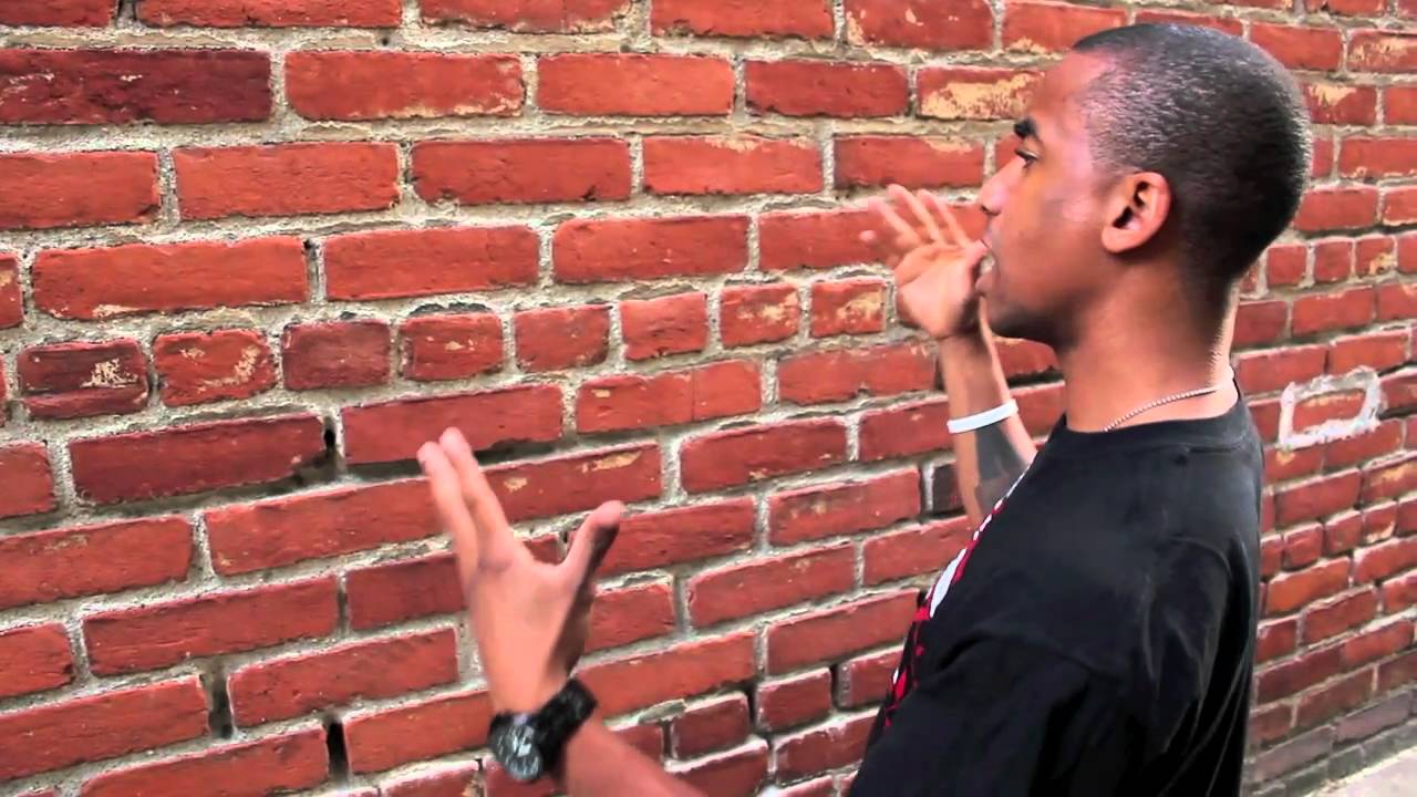 Talking To Wall meme template - A man stands in front of a large brick wall, hands raised mid-gesture, clearly in the middle of making an impassioned point.