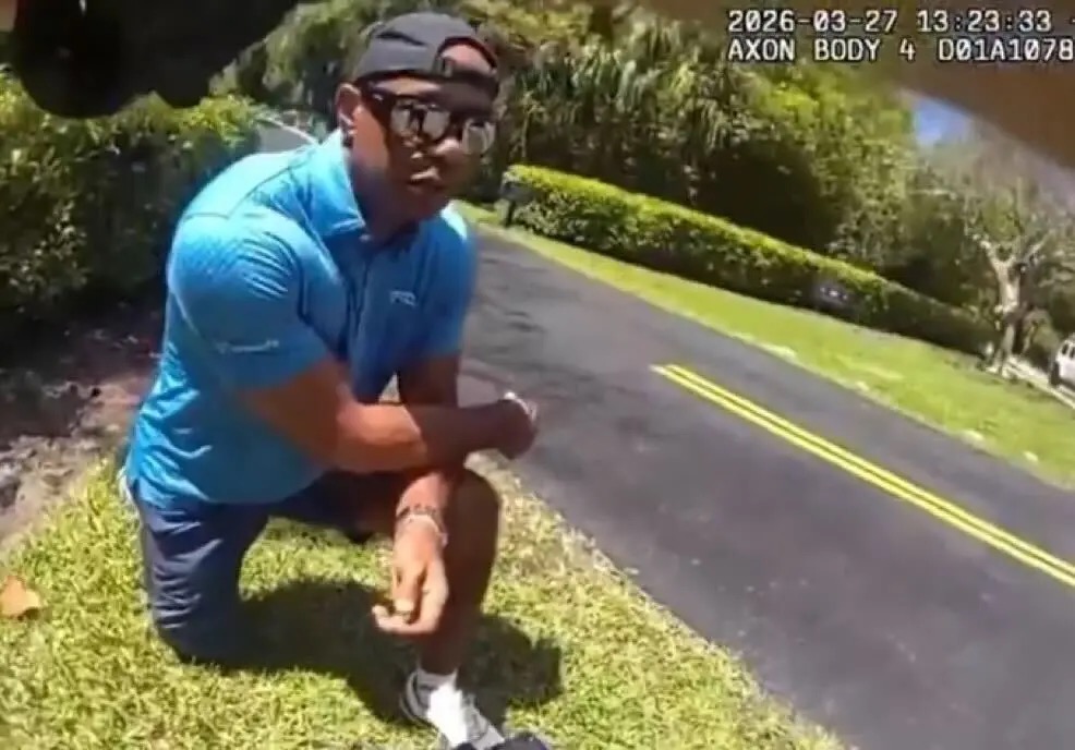 Tiger Woods Taking A Knee meme template - Body camera footage from March 2026 shows Tiger Woods crouched on a grassy curb wearing a blue golf polo, looking up toward t