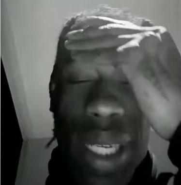 Travis Scott Murderer Of Fans meme template - A dark, low-lit image of Travis Scott performing on stage. The image has an ominous quality that reflects the cultural moment