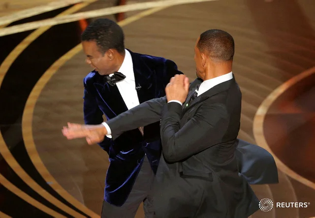 Will Smith Punching Chris Rock meme template - The 2022 Oscars, captured in one frame. Chris Rock stands on the left in a blue velvet suit, head turning from the impact. Wi